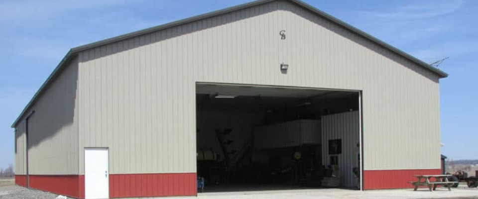 large tan and red pole building machine shed on farm