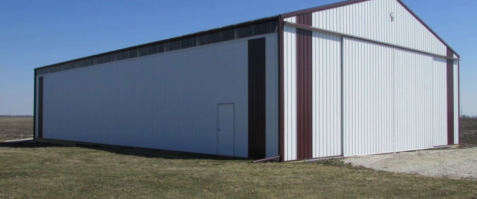 large white machine shed pole barn with sliding door