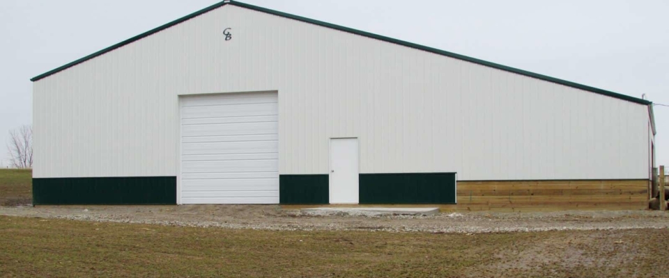white and green livestock post frame building
