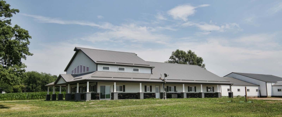 blue and gray pole barn house with horse arena attached