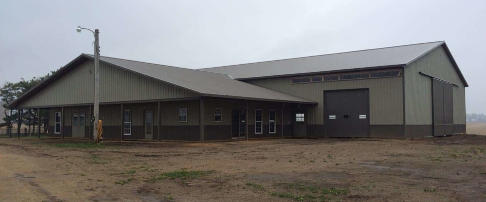 tan and brown horse barn with large arena post frame building
