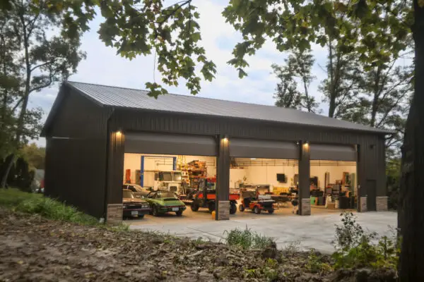 signature-series-dark-brown-pole-barn-three-bay-garage-lit-at-dusk